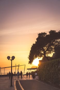 Dubrovnik, Croatia - April 2018 : People walking on a seafront promenade at sunset in Dubrovnik suburb of Lapad