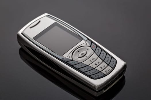 Old worn old-fashioned mobile phone on a gray background