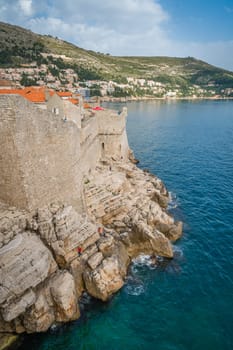 Dubrovnik, Croatia - April 2018 : Rocky coast alongside Dubrovnik Old Town massive defence walls of fortress Bokar