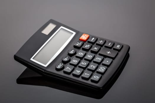 Old black old-style calculator on gray background