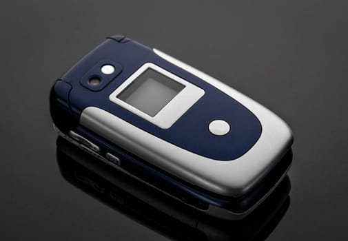 Old battered and scratched mobile phone on a gray background with reflection