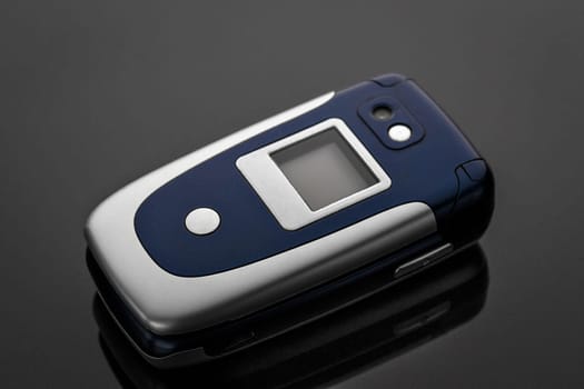 Old battered and scratched mobile phone on a gray background with reflection