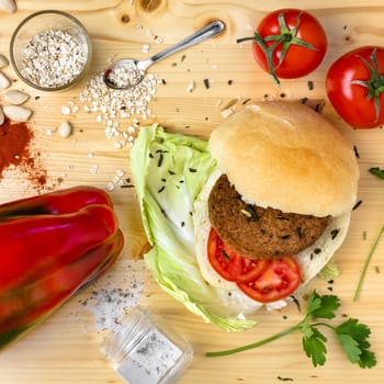 Vegan burger with fresh vegetables on wooden table, top view. Healthy fast food image theme.