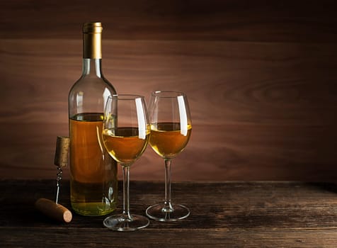 Bottle of white wine with wine glasses on wooden background