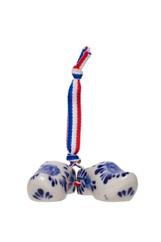 Holland wooden clogs. A pair of traditional dutch porcelain shoes with a ribbon flag isolated on a white background. Souvenir from Amsterdam.