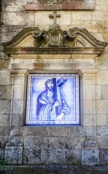 Niche with monochrome tile panel, blue on white, flanked by pilasters and topped by frieze and pediment interrupted by Latin cross in Castro Daire, Portugal