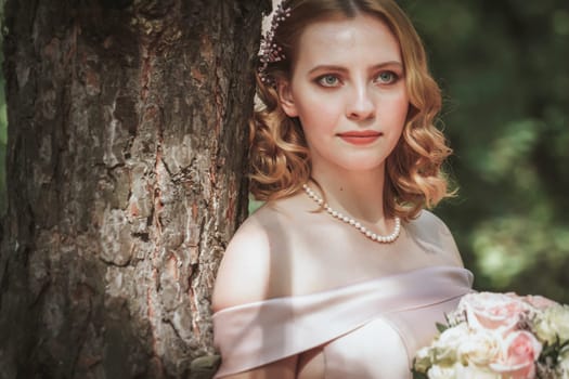 portrait of a beautiful bride standing near a tree.