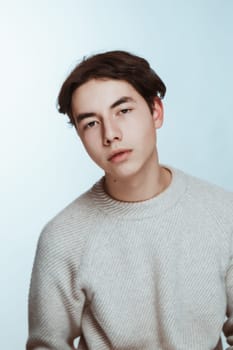 Studio portrait young man in grey sweater on white background.