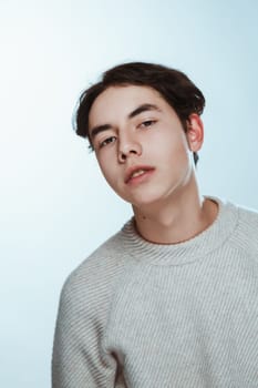 Studio portrait young man in grey sweater on white background.