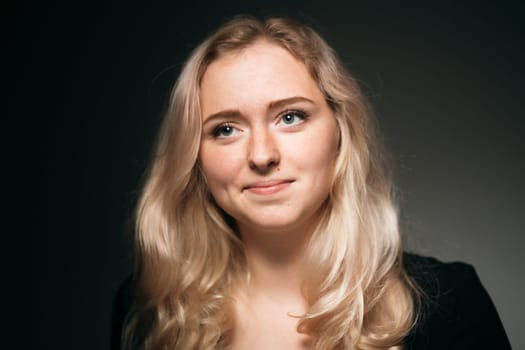 young girl blonde on a dark background.