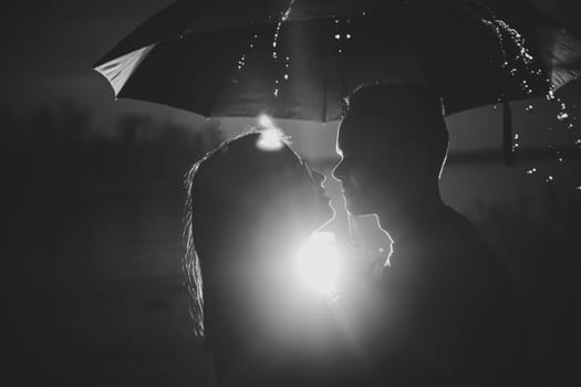 black white photo young man and woman under an umbrella and rain.