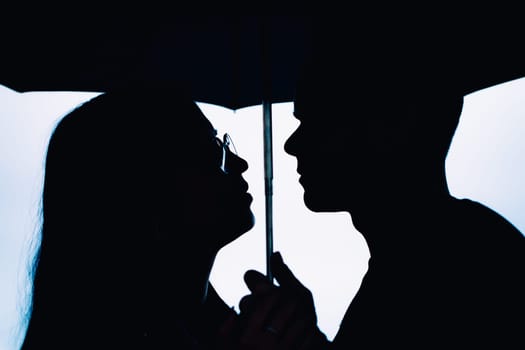 young man and woman under an umbrella and rain.
