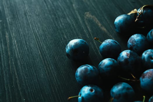 many fresh plums on black background close up.