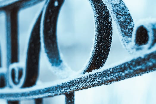 metal fence in hoarfrost on a blurred background.