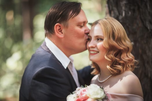 bride and groom kiss on the background of trees and forest.