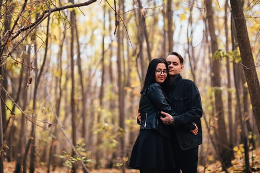 The girl and the guy are walking in the autumn forest.