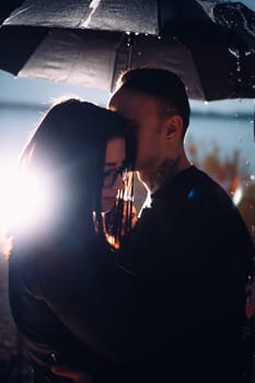 young man and woman under an umbrella and rain.