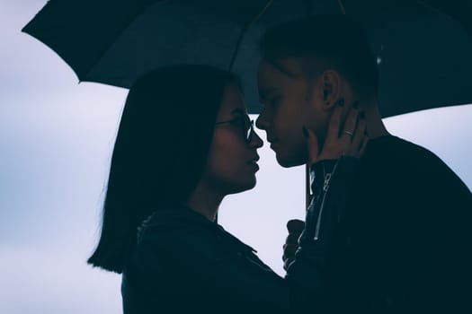 young man and woman under an umbrella and rain.