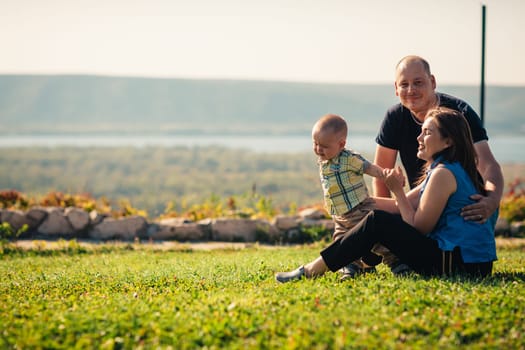Happy family with baby on green grass.