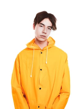 portrait of a teen guy in a yellow raincoat brunette in the studio.