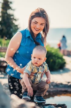 happy mother and toddler son near the fountain.