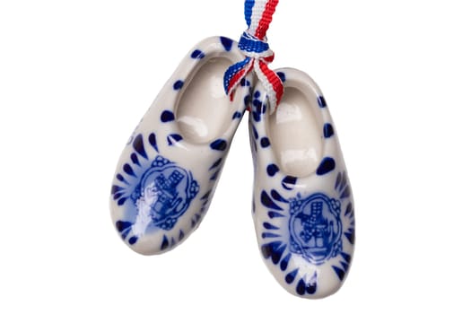 Holland wooden clogs. A pair of traditional dutch porcelain shoes with a ribbon flag isolated on a white background. Souvenir from Amsterdam. Macro.
