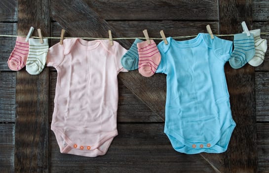 Baby clothing in pink and blue on rustic wooden background