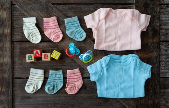 Baby clothing in pink and blue on rustic wooden background