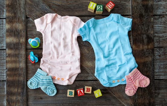 Baby clothing in pink and blue on rustic wooden background
