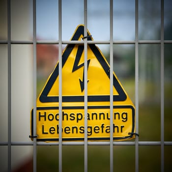 Sign with the inscription "high voltage danger to life"" on a fence"