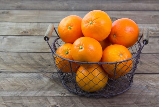 fresh oranges in a basket on wooden background