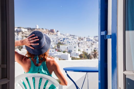 woman enjoying mykonos town view from terrace, Greece - summer holiday