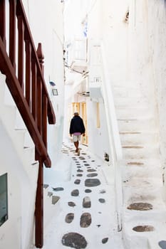 traditional narrow street in Mykonos with blue doors and white walls
