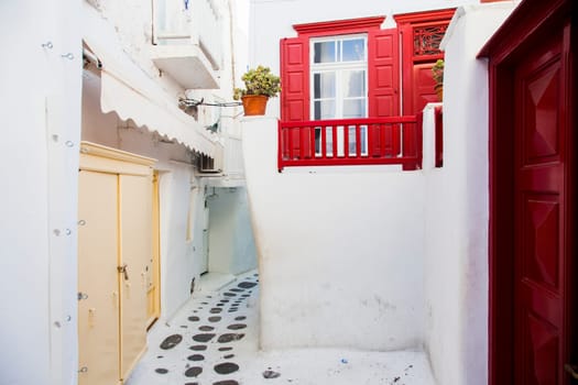 traditional narrow street in Mykonos with blue doors and white walls