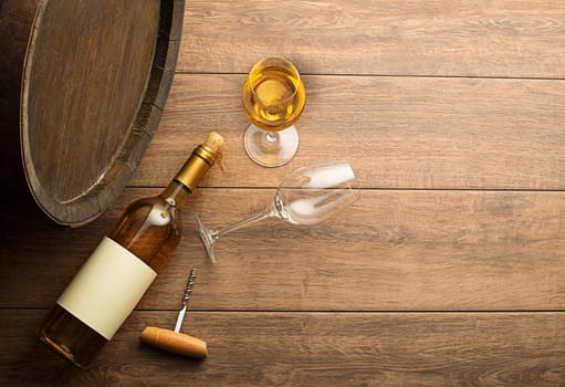 Bottle of white wine with label on old board. Wine bottle and glass with barrel background