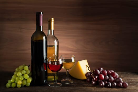 Glass and bottle of red and white wine on wooden background