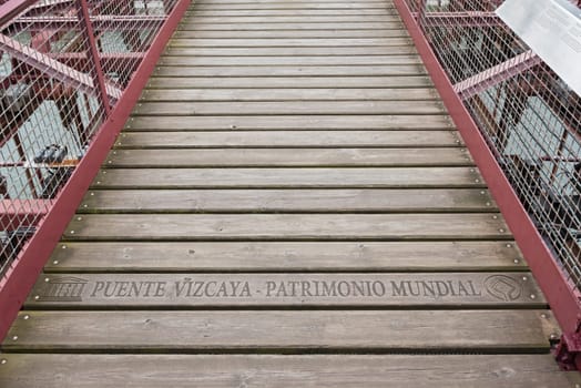 lettering (unesco puente vizcaya-patrimonio mundial) on the suspension bridge of bizkaia (puente de vizcaya) between getxo and portugalete above the ria de bilbao, spain