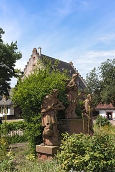 three sandstone figures in front of the monastery mill in seligenstadt, hesse, germany