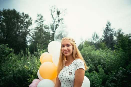 young girl with balloons on nature background.