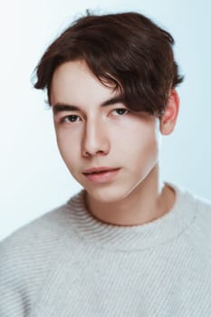Studio portrait young man in grey sweater on white background.