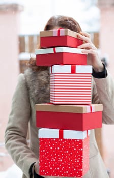 woman returning home from shopping holding pile of christmas present boxes