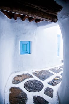 traditional narrow street in Mykonos with blue doors and white walls