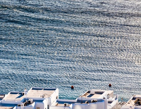 panoramic view of the Mykonos town harbor with famous windmills from the above hills on a sunny summer day, Mykonos, Cyclades, Greece