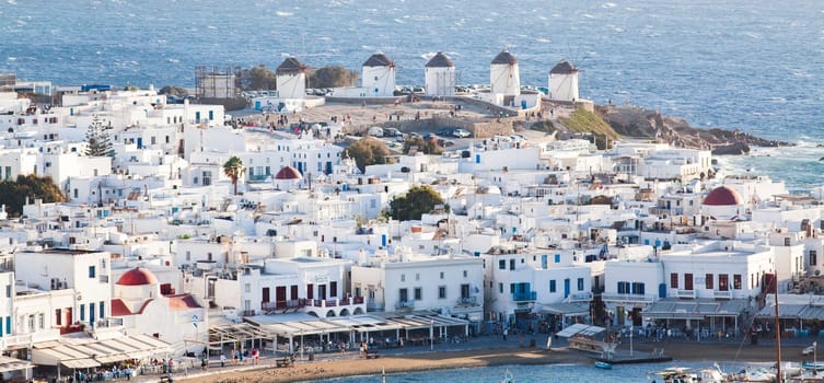 panoramic view of the Mykonos town harbor with famous windmills from the above hills on a sunny summer day, Mykonos, Cyclades, Greece