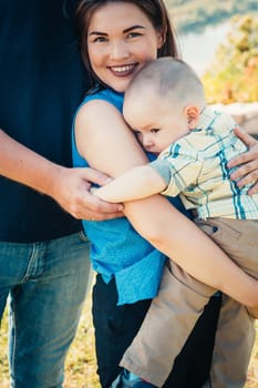Happy family with baby son on nature background.