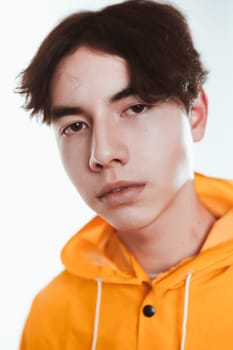 portrait of a teen guy in a yellow raincoat brunette in the studio.