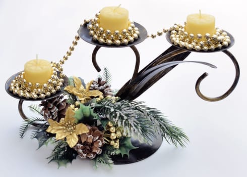 Newyear triple candlesticks with candles, shiny golden beads, flowers, pine cones and snow-covered fir branches on a white background.