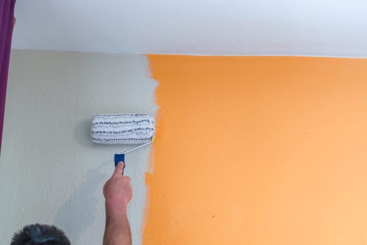 Hand with paint roller renovating. Painting a wall with white paint