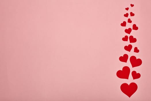 Red decorative hearts on a pink background with copy space. Top view. Valentine's Day card. Design element for romantic greeting card, wedding invitation