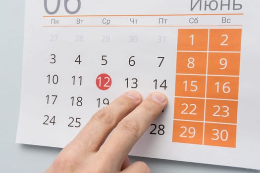 Fingers point to June 13 and 14 in the wall calendar